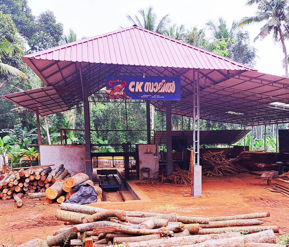 CK Sawmill in Kanjiramkulam, Trivandrum — the mill shed, signboard and stacked timber logs